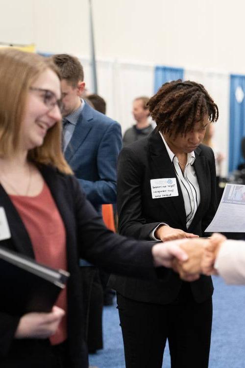 Four people in business attire shaking hands